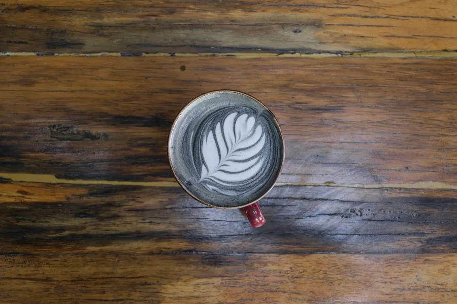 A cup of coffee with latte art on a rustic wooden table.
