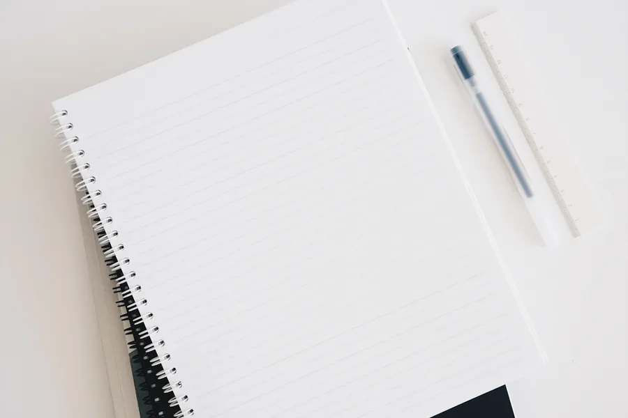 A notebook, pen, and ruler laid out on a clean desk.